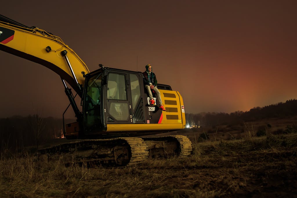 A person sitting on an excavator during the night in Greenville, Michigan. Tranquil rural setting.