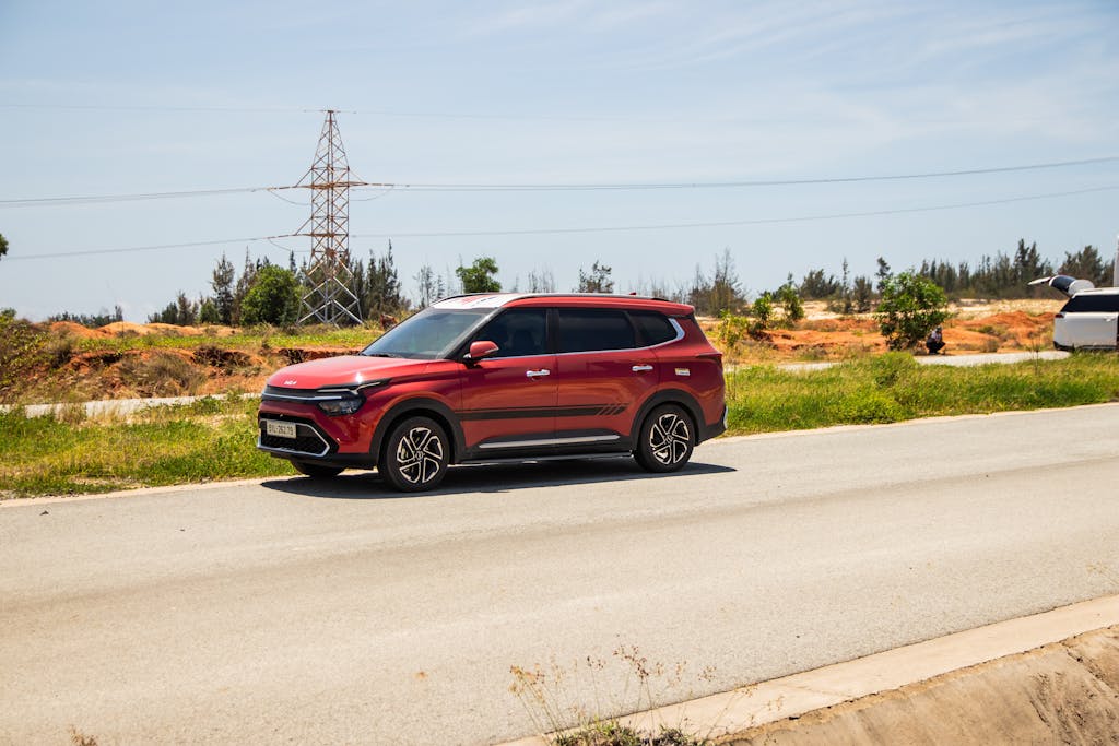 A red SUV driving on a sunny road in Phan Thiet, Vietnam, with a natural backdrop.