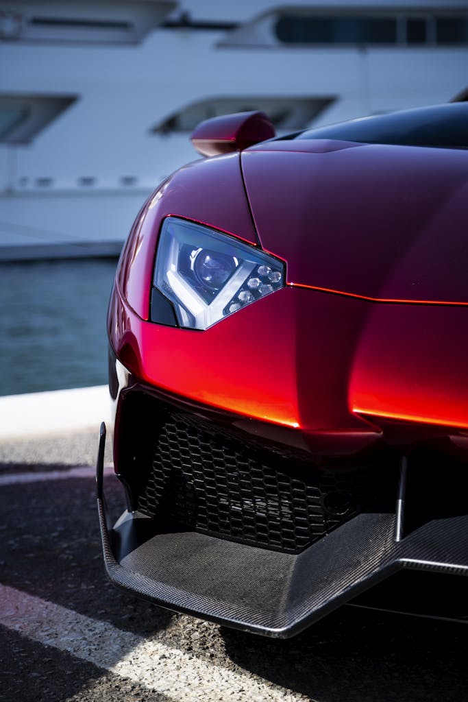 Close-up of a sleek red supercar parked at a marina in Spain.